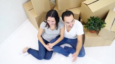 Karı koca yeni bir dairede, karton yığının yanında oturuyorlar..