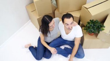 Genç bir adam ve kadının yeni bir evde birlikte rahatlayıp, yerde oturup, bir kutu dolusu kutuya yaslandıkları görüntüler..