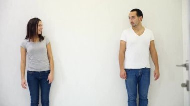 Beyaz arka planın farklı taraflarında duran çekici erkek ve kadın, aralarındaki boşluğu işaret ediyor, gülümsüyor..