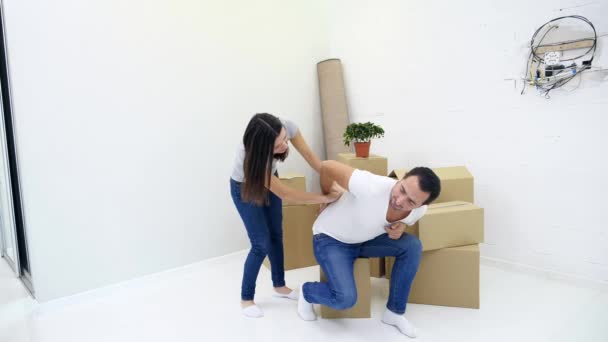 Mann hat Rückenschmerzen durch schweres Heben beim Einzug in neue Wohnung, seine Frau versucht ihm zu helfen. — Stockvideo