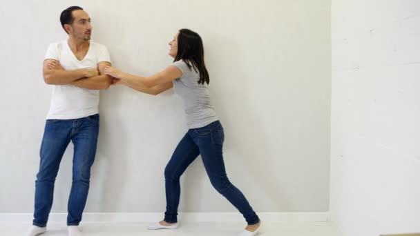 Atrakcyjny mężczyzna i kobieta stojący po różnych stronach białego tła, wskazujący na przestrzeń między nimi, podnoszący kciuki, uśmiechający się. — Wideo stockowe