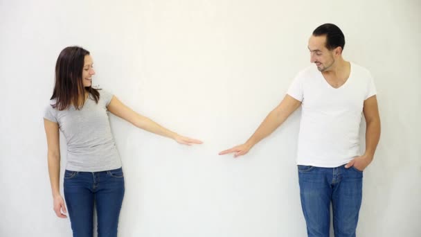 Brunette homme et femme debout sur fond de mur blanc et levant les mains, montrant la croissance et le succès . — Video