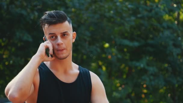 Un hombre guapo está en un parque de skate y al teléfono. Copiar espacio. De cerca. 4K . — Vídeos de Stock