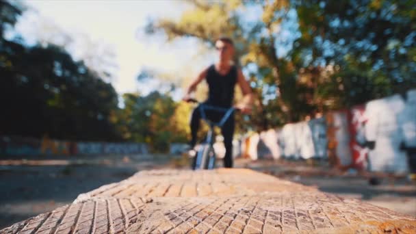 Man trekt zijn BMX fiets omhoog. Doe het wiel dicht. Lager wazig zicht. 4K. — Stockvideo