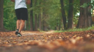 Erkekler yarışmadan önce parkta koşuyorlar ve sabah egzersizleri yapıyorlar. Bacaklarını kapat. Dikiz aynası. Uzayı kopyala 4K.