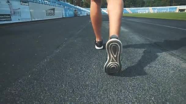 Men está corriendo alrededor del estadio haciendo ejercicios matutinos antes de la competición. Vista trasera. Cierra las piernas. Copiar espacio. 4K . — Vídeo de stock