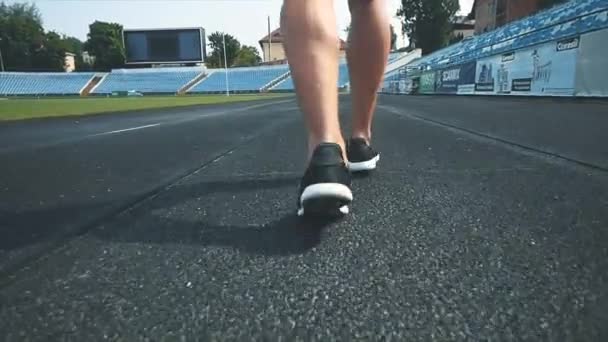 Män springer runt stadion gör morgonövningar innan tävlingen. Bakifrån. Stäng benen. Uppfattat utrymme. 4K. — Stockvideo