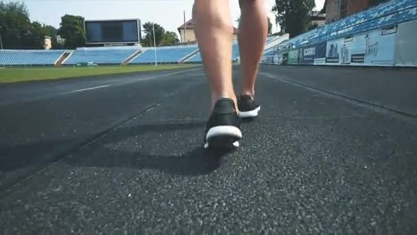 Homens estão correndo ao redor do estádio fazendo exercícios matinais antes da competição. Visão traseira. Fecha as pernas. Espaço para cópia. 4K . — Vídeo de Stock