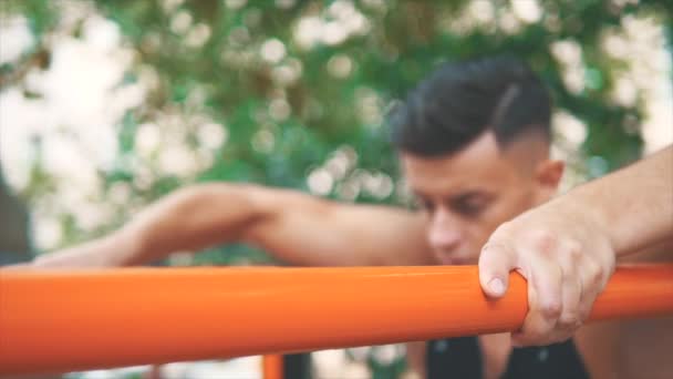 Primer plano del joven deportista haciendo ejercicio en las barras de paraller. Fondo borroso. Lento. En cámara lenta. Acción. 4K . — Vídeos de Stock