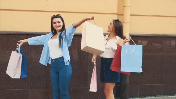 Zwei glückliche Mädchen mit Einkaufstüten prahlen mit Einkäufen und zeigen sie. Langsam. Zeitlupe. Kopierraum. 4K. — Stockvideo