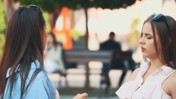 Two attractive young women are talking in a summer street. Close up. Side view. Copy space. 4K — Stock Video