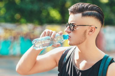 Dışarıdaki şişeden su içen bir adama yaklaş.