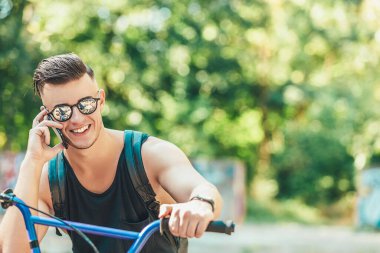 Şık bir adamın ara verip, sokakta bisiklet sürerken cep telefonu kullanması.