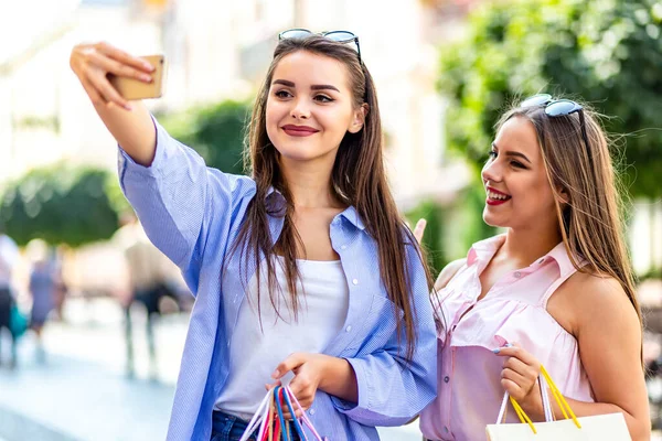 Best friends taking selfie and smiling lovely while shopping in city center.