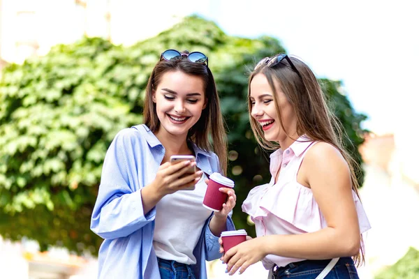 Attractive hipster girls in stylish sunglasses strolling in downtown in sunny weather, drinking coffee. — Stock Photo, Image
