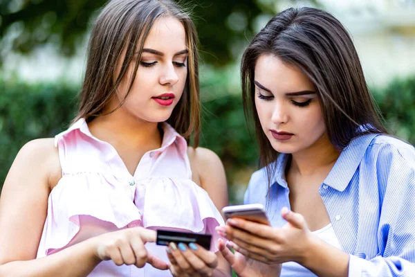Lovely female friends meeting on weekend, using smartphones and having fun in city center. — Stock Photo, Image