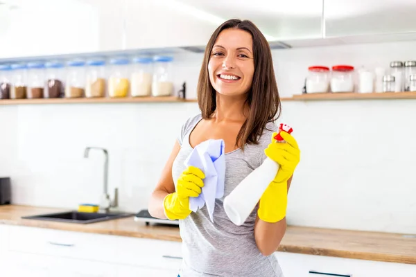 Ritratto di giovane casalinga che indossa guanti di gomma, tiene in mano una bottiglia di spray detergente e straccio, si sente piena di energia per rendere tutto super pulito . — Foto Stock