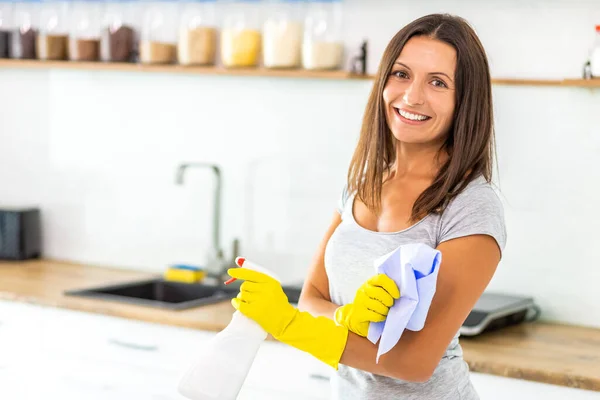 Очаровательная женщина в защитных перчатках со спреем и тканью для чистки кухни . — стоковое фото