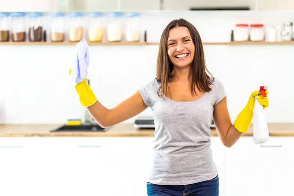 Piena di energia donna in piedi in cucina, alzando uno spray e straccio, godendo del risultato del suo lavoro di pulizia perché tutto splende ora . — Foto Stock