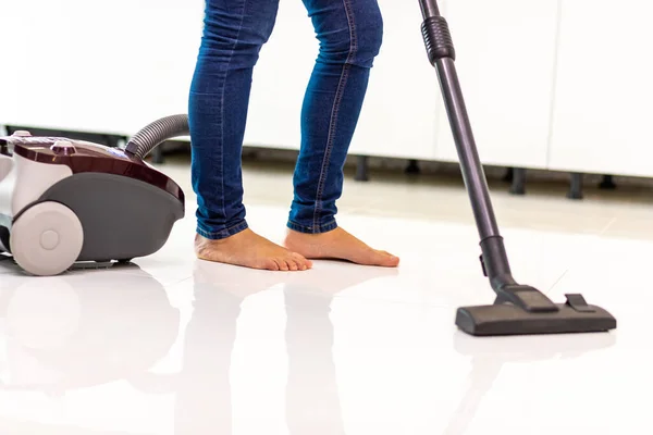 Обрезанный снимок женских ног, очищающих пол дома пылесосом . — стоковое фото