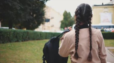 Yavaş ol. Uzun siyah örgülü sevimli ve genç bir turist gülümsüyor ve kameraya doğru dönüyor. Kapatın. Uzayı kopyala 4K.