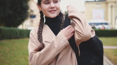 Uzun siyah örgülü sevimli ve genç bir turist bir turist sırt çantasını giydiriyor. Kapatın. Uzayı kopyala 4K.