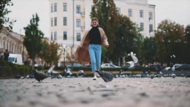 Sevimli kız güvercinlerle dolu meydanda koşuyor. Ağır çekim. Uzayı kopyala 4K.