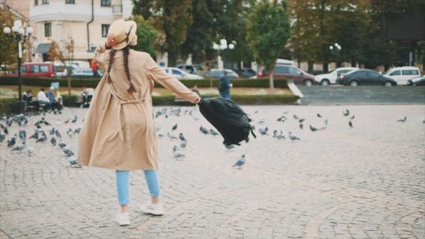 Lento. Adorable y joven turista con largas trenzas negras y sombrero en la cabeza sonríe y gira en la plaza. Copiar espacio. 4K . — Vídeos de Stock