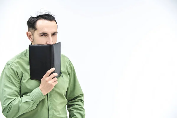 Hombre de negocios maduro mirando sobre el cuaderno negro con expresión facial sospechosa y desconfiada sobre fondo blanco con espacio para texto o producto . — Foto de Stock