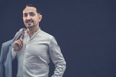 Siyah arka planda poz veren iyi giyimli bir adam..