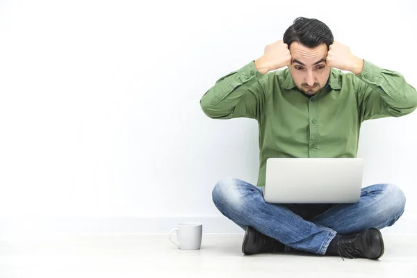 Omtänksam och stressig affärsman har svårt att arbeta, sitter på golvet med laptop på knä. — Stockfoto