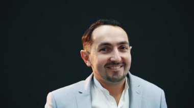 Modaya uygun mavi takım elbiseli yakışıklı genç adam duruyor, poz veriyor, aptal gibi ellerini sallıyor, aptal bir ifade takınıyor..