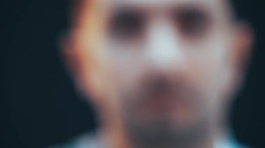 Kameraya bakan ciddi bir genç adamın yüzü bulanık ve berrak..