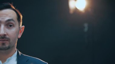 Genç komik adamın yarısı, kameraya bakıyor, gülümsüyor, kaşlarını kaldırıyor..