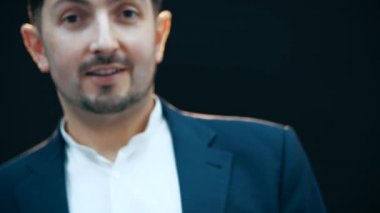 Yakışıklı, oyuncu, şık takım elbiseli adam zıplıyor, poz veriyor, ellerini kaldırıyor, komik surat ifadeleri takınıyor..