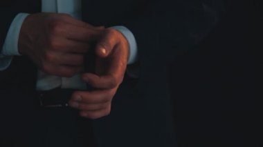 Yakışıklı genç adamın elleri gömleğinin kollarını düzeltiyor sonra da ceketini, iyi görünüp görünmediğine bakıyor..