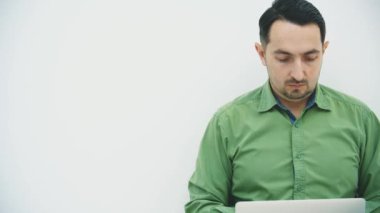 Ciddi bir genç adam çalışıyor, daktilo çekiyor, kameraya bakıyor, şüpheli bir şekilde kaşlarını temizliyor..