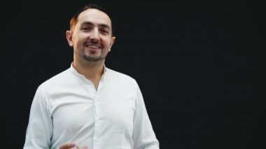 Komik genç adam kameraya bakıyor, aptalca, ceketini omzuna koyuyor, sonra da siyah arka planda kayboluyor..