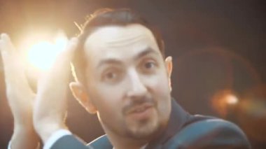 Komik, neşeli genç iş adamı aptalca hareket ediyor, ellerini çırpıyor, kameraya bakıyor, poz veriyor..