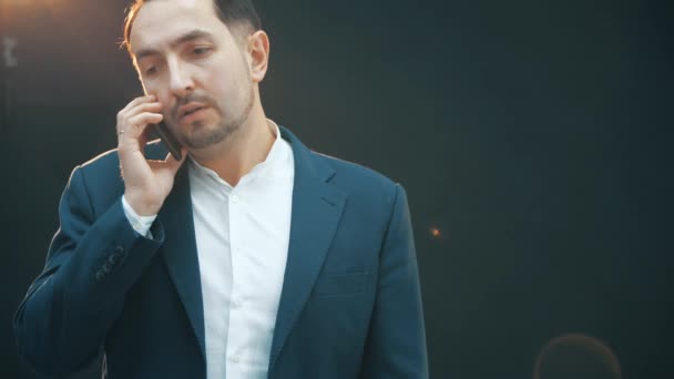Серьезный молодой человек, говорящий по телефону, меняющий свой деловой костюм . — стоковое видео
