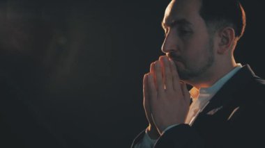 Ciddi bir şekilde konsantre olmuş, yoğun düşünme sürecine katılmış, dua eder gibi el ele tutuşmuş, yardım isteyen biri..