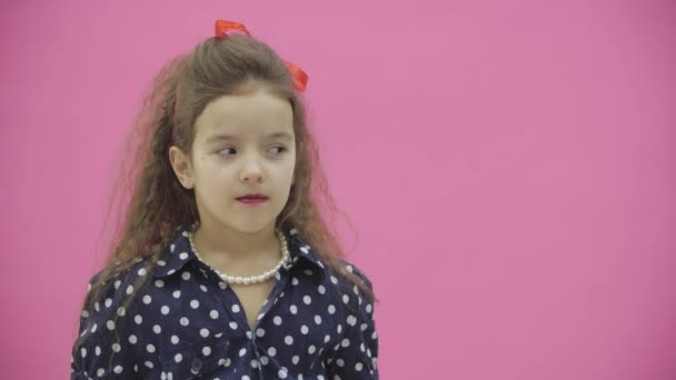 흰색 폴카 점 이 있는 검은 블라우스를 입은 핑크 색 배경의 소녀가 외진 곳에서 찍은 4k 느림보 비디오. — 비디오