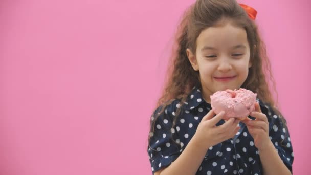 Маленька дівчинка їсть смачні пончики у відео з уповільненням 4k . — стокове відео