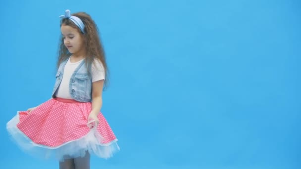 4K video 'da mavi arka planda duran küçük kız. — Stok video