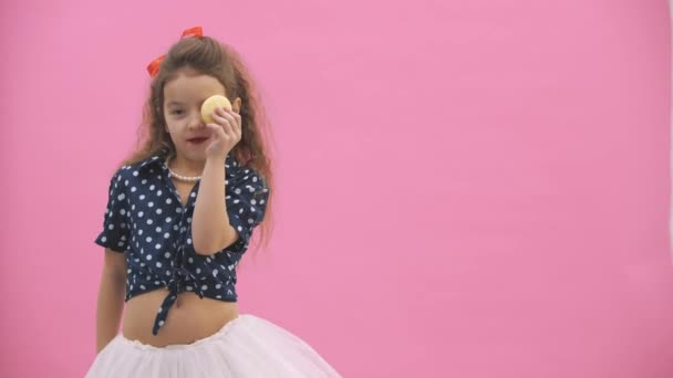 4k video in cui la piccola ragazza con i capelli ricci mangia un amaretto giallo . — Video Stock