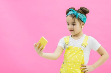 İyi giyimli bir kız sarı telefonunu kullanarak selfie çekiyor..