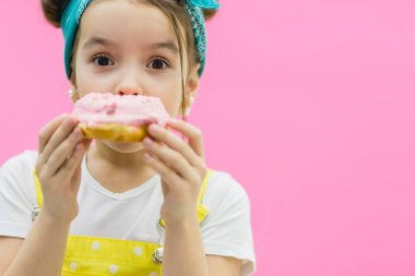 Çöreğin arkasına saklanan küçük bir kız. Pembe arkaplan