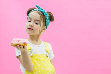 Sarı tulumlu kız jöleli çöreğe bakıyor..