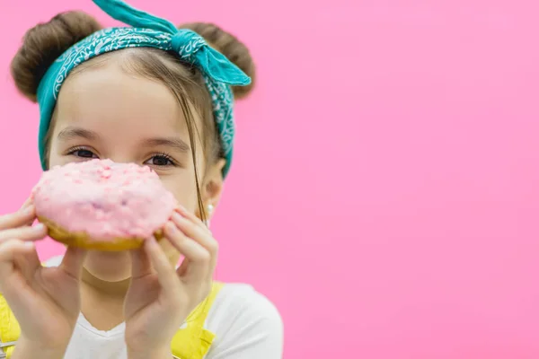 Little girl has a donut in her hands. — Stock Photo, Image