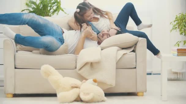 4k video di mana ayah bermain dengan putrinya berbaring di sofa. — Stok Video